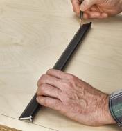 Marking the middle of a wooden panel with a pencil and a Veritas edge rule set on top of the panel