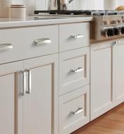 Satin nickel cup pulls, handles and knobs mounted on kitchen cupboards