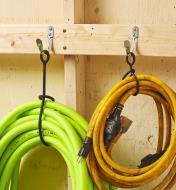Two KuVu straps hold a hose and an electrical cord on wall hooks