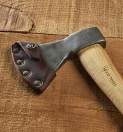 A carving axe with the leather sheath attached rests on a wood background