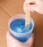 A batch of blue two-part epoxy being mixed in a 1-pint measuring and mixing cup