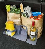 Cargo holder brackets holding grocery bags and juice and wine bottles upright in a car’s cargo area