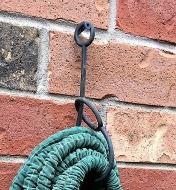 A KuVu strap hangs a bundle of rope from a screw on a brick wall