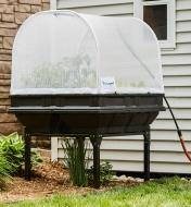 A Vegepod container garden with a base and the cover closed sits in a garden