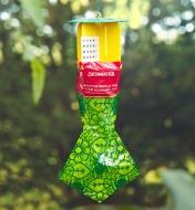 A yellow, red, and green Japanese beetle trap hangs from a tree