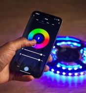 A smartphone being used to control a set of colored lights that are on the floor
