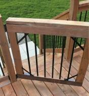 A gate constructed using hardware from the heavy-duty gate bracket kit is installed on a deck rail post