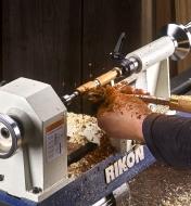 A woodworker turns a pen on a Rikon model 70-105 mini lathe