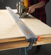 A clamp edge attached to a sheet of wood that is being cut by circular saw