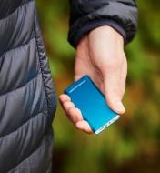 A blue rechargeable handwarmer held in someone’s hand