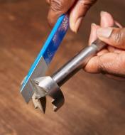 A diamond paddle hone being used to sharpen a saw-tooth drill bit