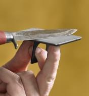 Close-up view of fingers gripping the fold-out handle of the credit-card size sharpener