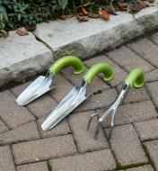 A trowel, bulb trowel and cultivator on a cobblestone surface