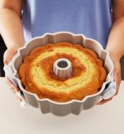 Holding up a baked cake in a Bundt pan
