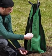 Zipping up the 20 gallon PVC tree watering bag wrapped around a tree base