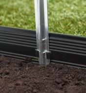 A length of everlasting aluminum edging secured in the ground with a stake