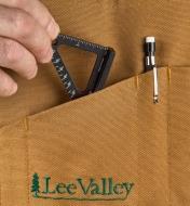 A woodworker slips a Veritas 2 1/2"" Pocket Square into the pocket of a workshop apron
