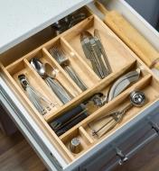 An open kitchen drawer containing a drawer insert filled with utensils