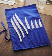 Three knives lying on a cutlery roll and four knives inside the roll
