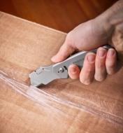 Using the 3-in-1 knife with one of the included utility-knife blades to cut open a cardboard box