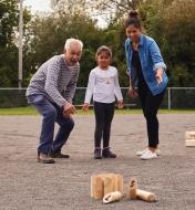 A man, a woman and a girl playing Mölkky outdoors