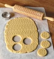Cookie cut-outs from dough embossed by the holiday sweater rolling pin