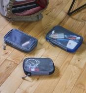 Three travel organizers on a wood floor next to a large backpack