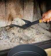 Using the fireplace shovel to remove ashes from a fireplace