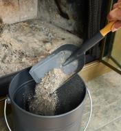 Pouring ashes from the fireplace shovel into an ash can