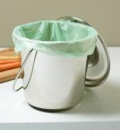 A stainless-steel compost pail lined with a compostable bag sits on a countertop