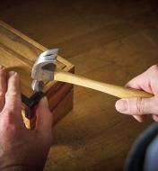 Holding a wooden box steady as a hammer drives a small nail to attach a box corner