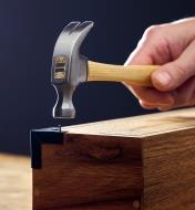 Using a 5 oz hammer to attach a box corner to a wooden box with a small nail