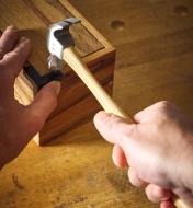 Using a 5 oz hammer to drive a small nail into a wooden box