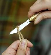 Using a Rybička knife to cut a piece of twine