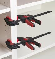 Two clamps attached to a shelving unit