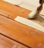 Using a brush to apply Osmo bangkirai decking oil to a wooden deck