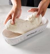 Placing bread dough in a proofing basket fitted with a cotton-blend liner