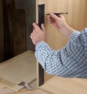 Standing a shop rule on end to lay out hinge locations on an inside wall of a cabinet