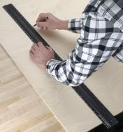 Using a pencil and a 39" shop rule to mark a cut line on a sheet of plywood 