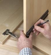 Using a pencil and a 12" shop rule to mark hinge locations on an inside wall of a cabinet 