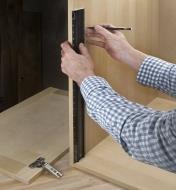 Standing a shop rule on end to lay out hinge locations on an inside wall of a cabinet 