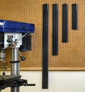 Four sizes of Veritas Imperial/metric shop rules hung on a pegboard near a drill press