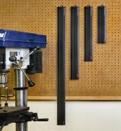 Four sizes of Veritas metric shop rules hung on a pegboard near a drill press