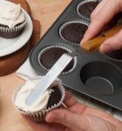 Using the blade tip of the spatula to spread frosting on a cupcake