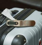 A digital luggage scale rests on top of a suitcase
