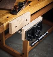 A quick-release vise mounted on a workbench, with user-made wooden attachments on the jaw faceplates