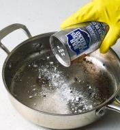 Sprinkling Bar Keepers Friend onto a pan’s cooking surface 