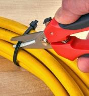 Using shears to cut a zip tie around an electrical cord