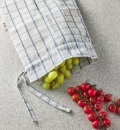 Grapes in an open bread storage bag with cherry tomatoes sitting next to it