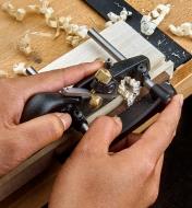 A left-hand box-maker’s plow plane being used to cut a groove on a piece of wooden stock